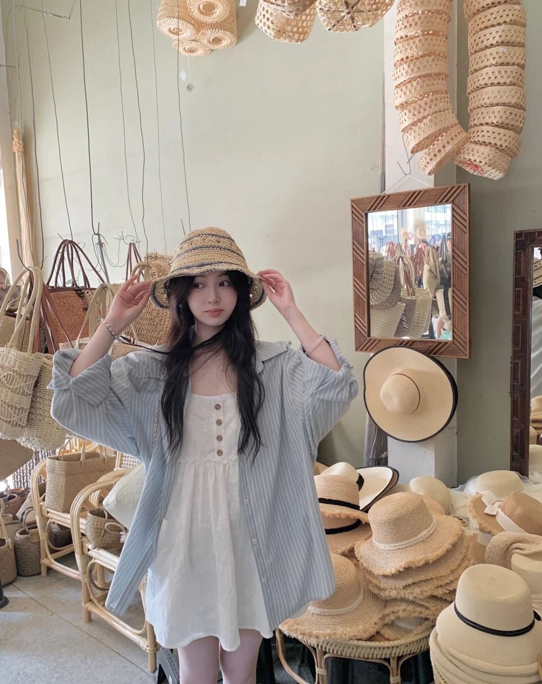 cô gái tay đang giữu mũ mặc váy đầm và áo sơ mi khoác ngoài